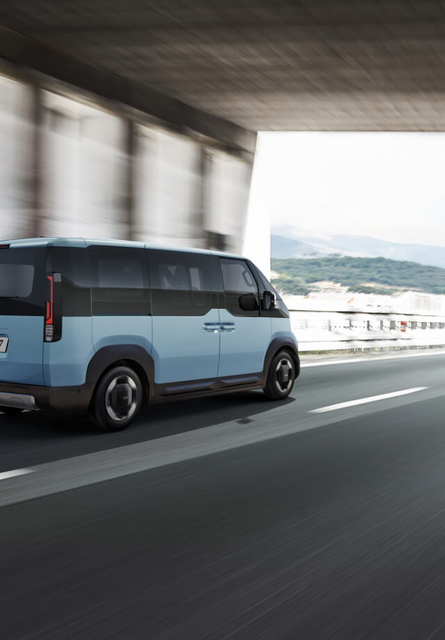 Rückansicht des Kia PV5 Passenger, der auf der Autobahn fährt – mit einem weiteren Kleinbus voraus.